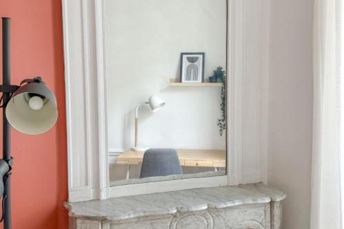 - un miroir installé au-dessus d'une cheminée dans l'établissement Flexliving - room - Hameau, à Paris
