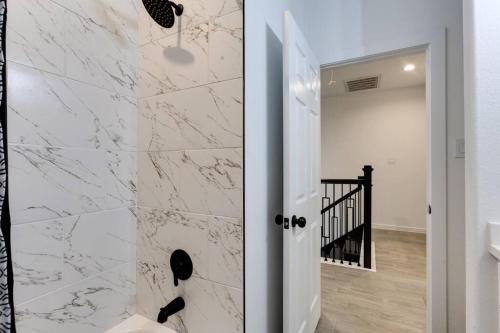 a bathroom with white marble walls and a walk in shower at Lé Luxe Maison -3BR 2 BA- Medical Center and Downtown HTX in Houston