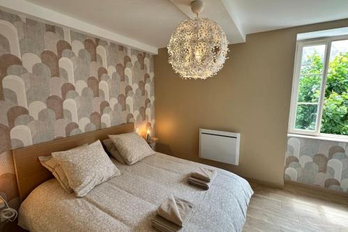 une chambre avec un grand lit et un lustre dans l'établissement Aux Champs Perdrix, à Couchey