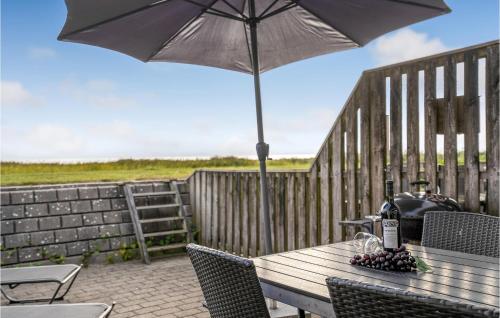 a wooden table with an umbrella on a patio at 1 Bedroom Beautiful Apartment In Rømø in Rømø Kirkeby