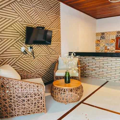 a living room with two chairs and a tv on a wall at Velho Chico in Icaraí