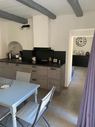 une cuisine avec une table et des chaises bleues et une cuisine avec une horloge dans l'établissement Entre lavande et oliviers, à Plaisians