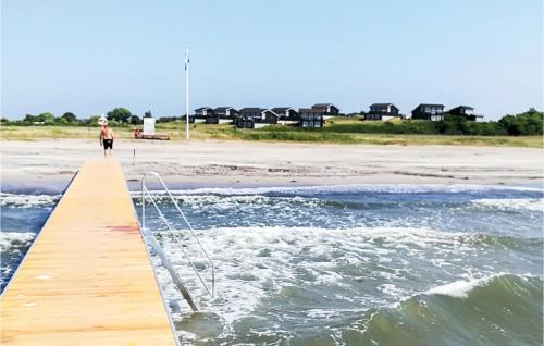 a woman walking on a pier on the beach at Holiday Home Strandgårdsvej Bagenkop X in Bagenkop