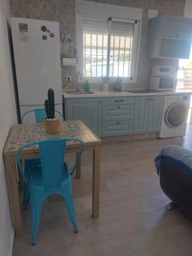 a kitchen with a table and a blue chair at La casita de Valeria in El Palmar