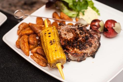 a plate of food with a steak and corn and potatoes at Landgasthof zur Quelle in Seeshaupt