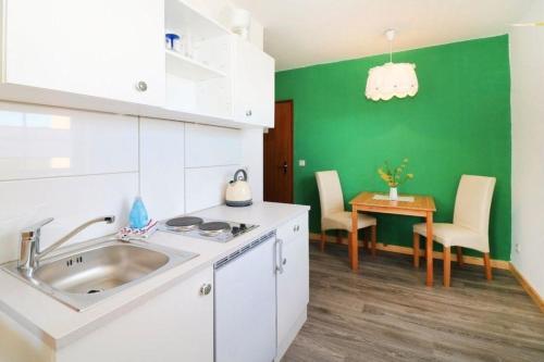 eine Küche mit Spüle und Tisch mit Stühlen in der Unterkunft Ferienwohnung 2 Personen Hund willkommen in Lütow