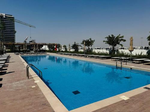 a large blue swimming pool with chairs and a building at Golfville LighthouseDubai Hills in Dubai