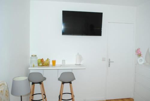 une cuisine blanche avec des tabourets et une télévision au mur dans l'établissement Beautiful decorated Classy Appartment, Évry-Courcouronnes