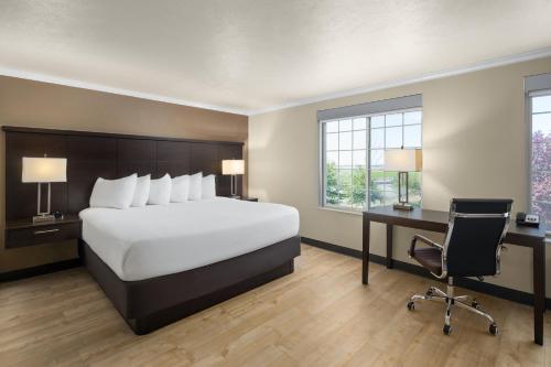 a bedroom with a bed and a desk and a chair at Ramada by Wyndham Moses Lake in Moses Lake