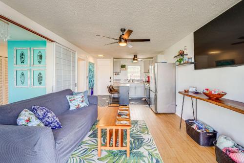 a living room with a blue couch and a kitchen at Kailua-Kona Condo with Balcony Walk to the Beach! in Kailua-Kona