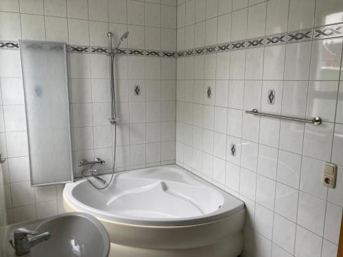 Baño blanco con lavabo y bañera en Gästewohnung am Stadtpark, en Meerane