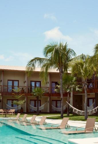 a resort with a swimming pool and chairs and palm trees at Terrasa Solar Hotel in Icaraí