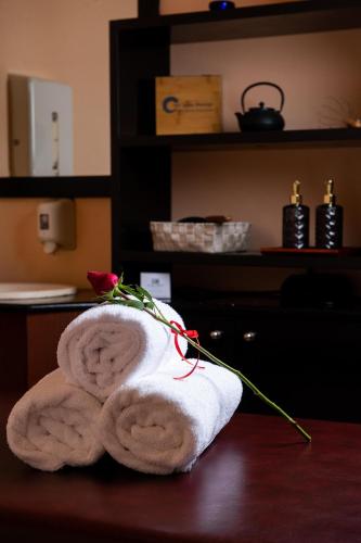 a stack of towels sitting on a table with a rose at Alexandros Palace in Ouranoupoli