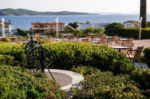 a park with tables and chairs and the ocean at Alexandros Palace in Ouranoupoli
