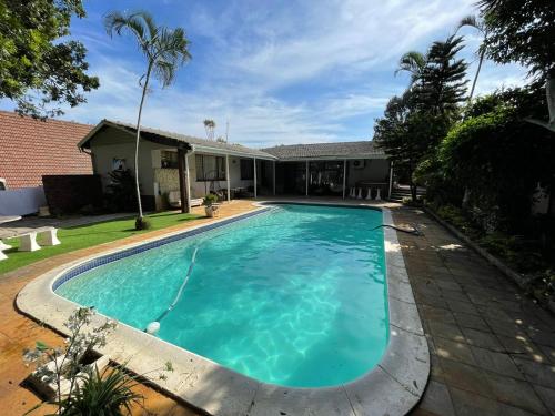 a swimming pool in front of a house at Mbathos guesthouse in Durban