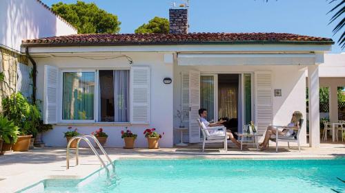 two women sitting in chairs next to a swimming pool at Landhaus mit Garten, Sonnenterrasse sowie überdachter Terrasse und Pool in Strandnähe in Cala Ratjada