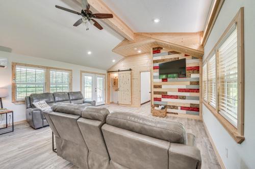 a living room with a couch and a flat screen tv at Secluded Broken Bow Cabin with Fishing Pond and Views! in Broken Bow