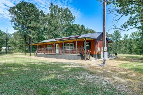a red house with a porch and a pole at Secluded Broken Bow Cabin with Fishing Pond and Views! in Broken Bow