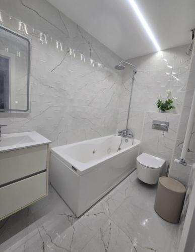 a white bathroom with a tub and a toilet at MyHome in Noja