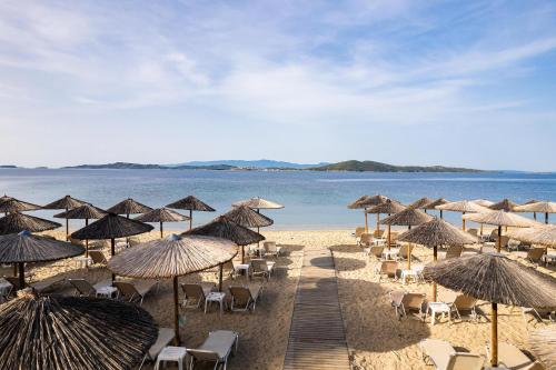 a beach with chairs and umbrellas and the ocean at Alexandros Palace in Ouranoupoli