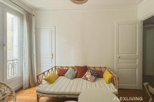 - un canapé avec des oreillers colorés dans l'établissement Flexliving - room - Caulaincourt, à Paris
