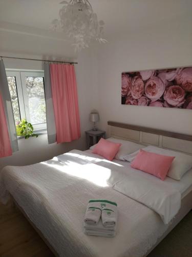 a bedroom with a large white bed with pink pillows at Apartmá U rybníčku in Dolní Dunajovice