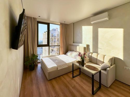 a room with a bed and a couch and a window at Apart Hotel Acropolis in Odesa