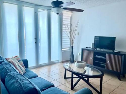 a living room with a blue couch and a table at Oceanview Costa del Mar Condo with Pool and Smart TV in Pole Ojea