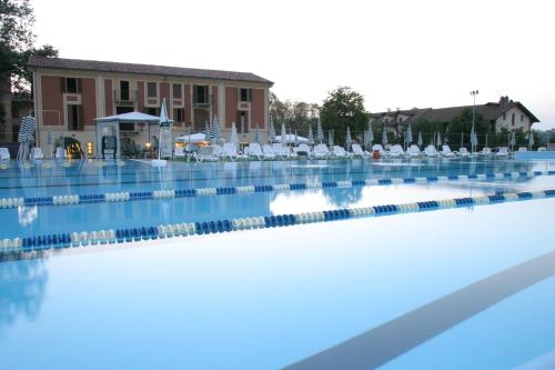 einem großen Pool mit weißen Stühlen und einem Gebäude in der Unterkunft Villa Scati Apartments in Melazzo