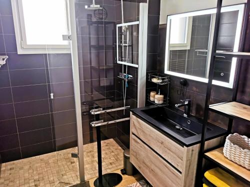 une salle de bain avec un lavabo noir et un miroir dans l'établissement L Oiseau du Paradis, à Les Sables-dʼOlonne