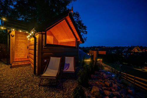 a couple of chairs in front of a house at night at Góralska Chatka 3 Highland Cottage - Jacuzzi, Sauna, Split AC, Private parking, Mountains View in Zakopane