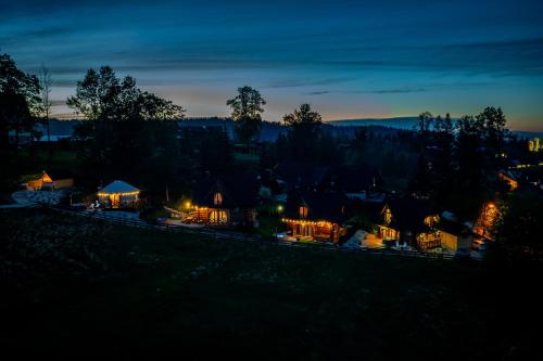 a group of houses lit up at night at Góralska Chatka 3 Highland Cottage - Jacuzzi, Sauna, Split AC, Private parking, Mountains View in Zakopane