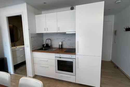 une cuisine blanche avec des armoires blanches et un évier dans l'établissement Studio Juan-les-Pins à 50m plage, à Antibes