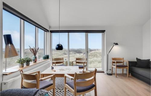 a dining room with a table and chairs and windows at Five-Bedroom Holiday Home Løkken With A Room Hot Tub 04 in Løkken