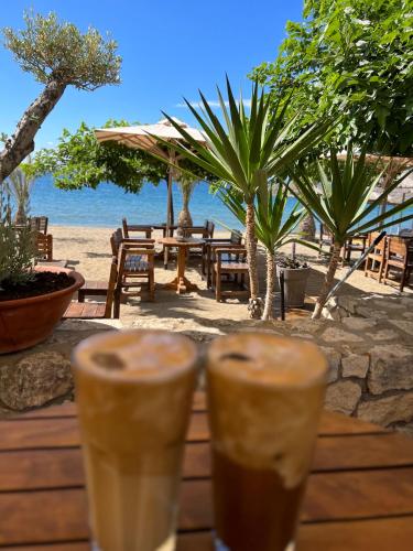 two drinks on a wooden table near the beach at Carpe Diem Apartments in Psakoudia