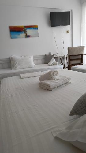two white beds with towels on top of them at Polyxeni Apartments & Rooms in Qeparo