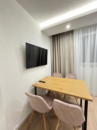 a room with a wooden table with chairs and a television at Apartman Kosuta Lux Mountain View in Tjentište