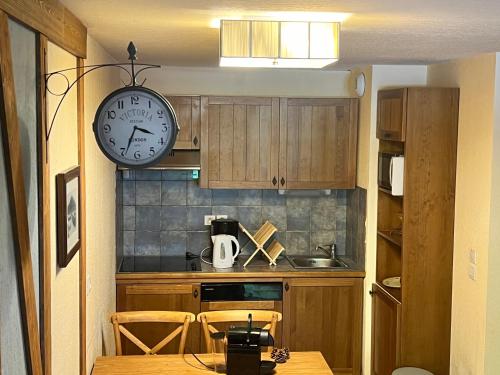 a kitchen with a clock on the wall and a table at Séjour SPA inclus au centre de St Lary in Saint-Lary-Soulan