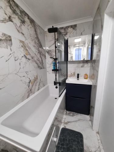 a bathroom with a white tub and a sink at Stylish London Apartment & Free Parking in London
