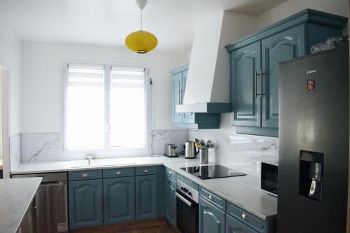 une cuisine avec des placards bleus et une fenêtre dans l'établissement La citadine Havraise, au Havre