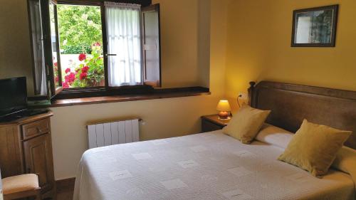 a bedroom with a bed and a window and a television at Casa de Aldea El Frade in Ribadesella