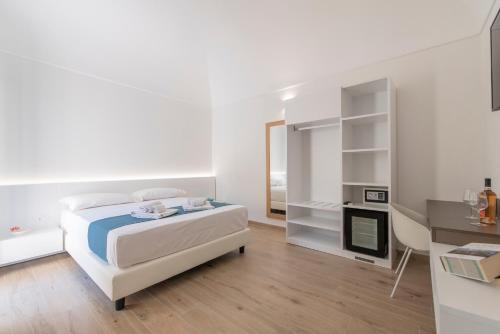 a white bedroom with a bed and a desk at Room 86 in San Vito lo Capo