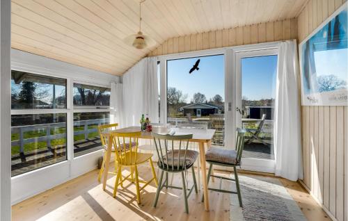 a dining room with a table and chairs and windows at Holiday Home Humlevænget Hejls V in Hejls