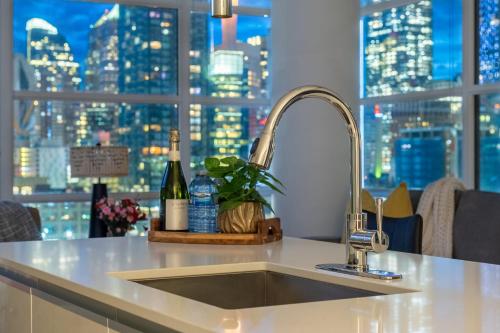 a kitchen sink with a view of a city skyline at "The Draper" - Luxury Corner Unit w Tower View, - Near Stampede, Saddledome, BMO Centre! FREE Parking, Banff Pass, & Wine! in Calgary