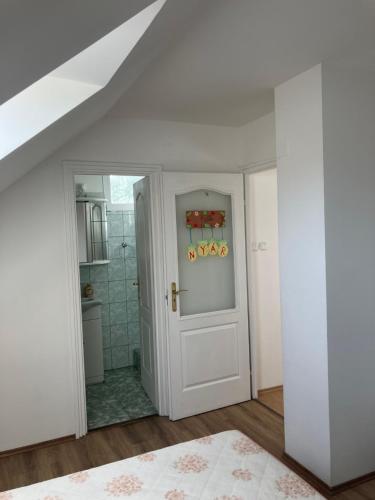 a bathroom with a white door and a shower at Tőserdei Vendégház in Lakitelek