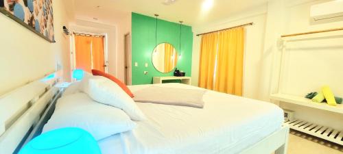 a bedroom with a white bed and a green wall at Blue Mango Beach Hotel in Guachaca