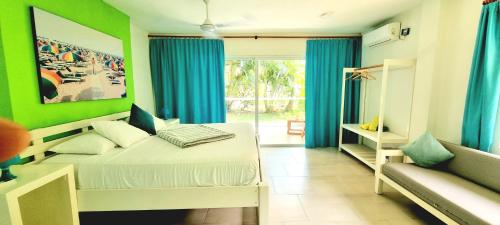a bedroom with green walls and a bed and a couch at Blue Mango Beach Hotel in Guachaca