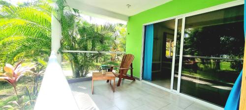 a porch with a chair and a green wall at Blue Mango Beach Hotel in Guachaca