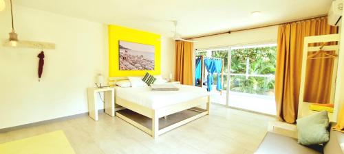 a bedroom with a white bed and a large window at Blue Mango Beach Hotel in Guachaca