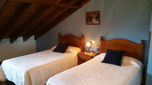 a bedroom with two beds and a table with a lamp at Casa de Aldea El Frade in Ribadesella